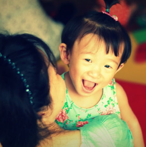 A smiling young child being held by a caregiver.
